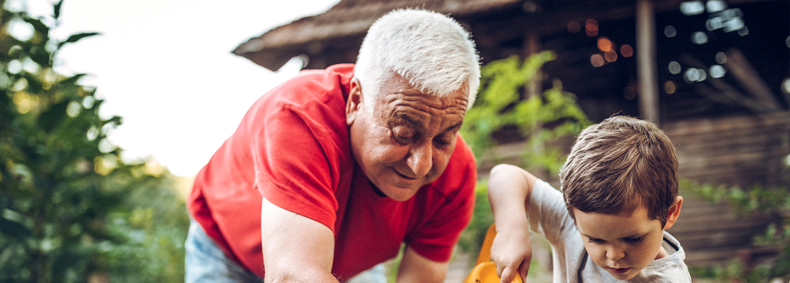 Grandfather and grandson playing in backyard with gardening tools