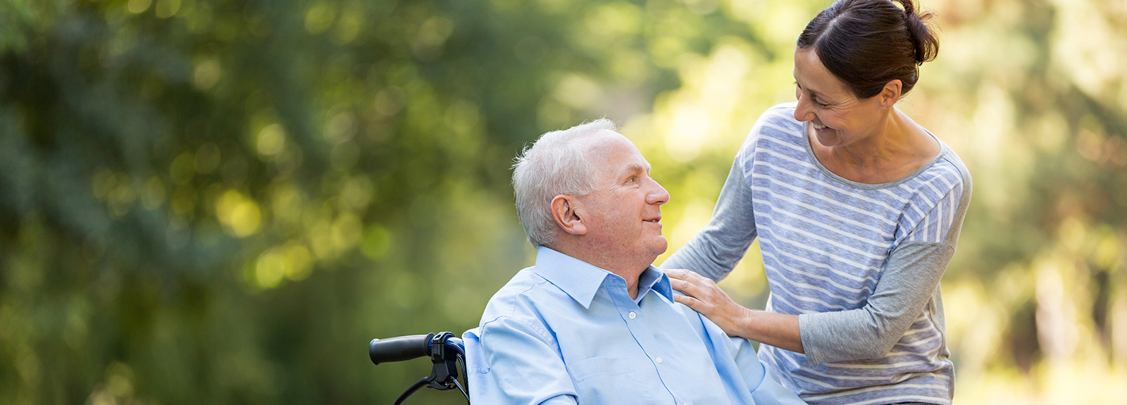 Senior man sitting on a wheelchair with caregiver